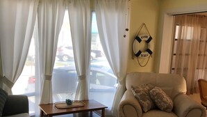 Ein Wohnzimmer mit Deckenventilator, einer Couch, einem Sessel, einem Couchtisch und einem Teppich.