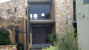 Un edificio moderno de dos pisos con fachada de piedra, ventanas amplias y una puerta de entrada oscura.
