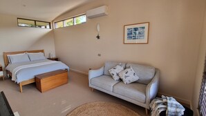 Un dormitorio con cama, sofá, mesita de noche, lámpara y ventana.