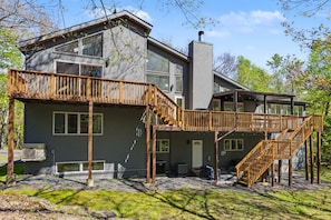 A modern two-story house with a wooden deck and a chimney.