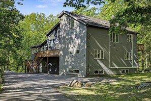 A two-story building with a wooden deck and a garage. - Modern Stream-front property with hot tub. (Bushkill)