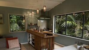 A modern kitchen with a wooden island, pendant lights, and large windows with tropical views.