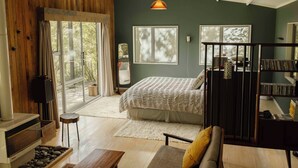 A modern bedroom with a large bed, a fireplace, and a view of the outdoors.