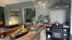 A modern kitchen with a central island, stainless steel appliances, and a window with a view of greenery.