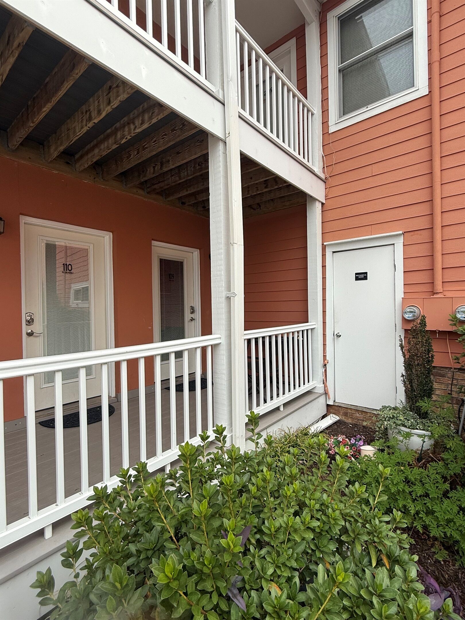 A two-story building with a white balcony, a red exterior, and a door labeled "110".