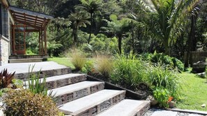 Un jardín con escalones de piedra que conducen a una pérgola de madera.