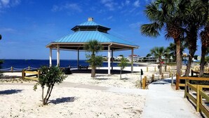Un kiosque de plage avec un toit bleu, entouré de palmiers et offrant une vue dégagée sur l’océan.