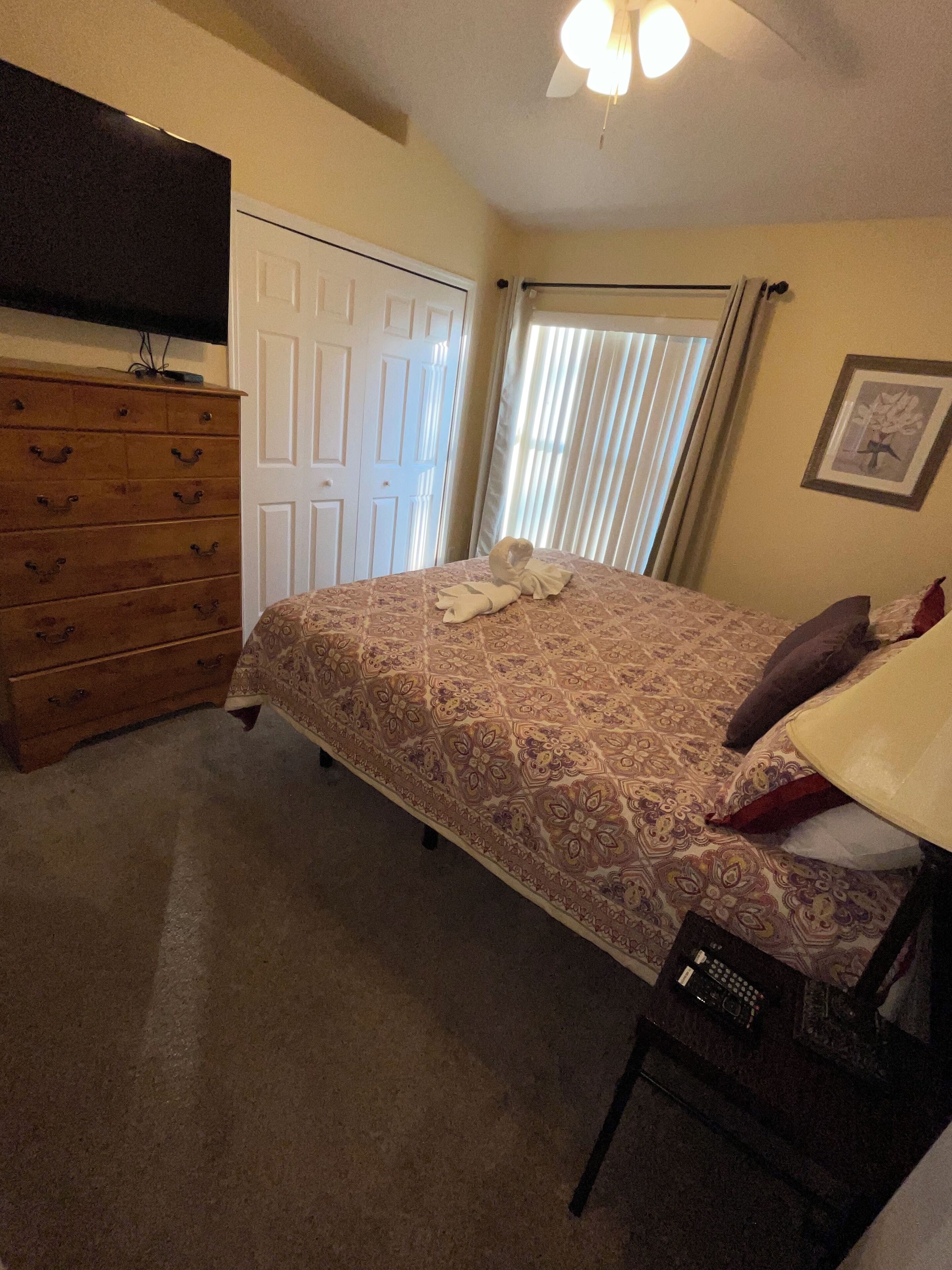 Un dormitorio con cama, cómoda y televisor de pantalla plana montado en la pared.