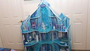 En miniaturedukkehus med et 'FROZEN'-skilt, flere rum og en trappe.