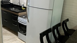 Une cuisine avec un réfrigérateur blanc, une cuisinière, un évier et une chaise.