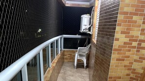 Un couloir étroit au sol carrelé, avec une rambarde en métal et un mur en briques.