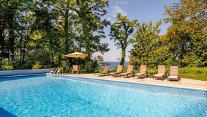 A clear blue pool with lounge chairs and a canopy, surrounded by trees and a view of the sea. - Spa House:On Lake Michigan w/ Pool, Hot Tub, Sauna (Benton Harbor)
