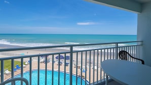 Ein Balkon mit Meerblick, ein Pool und Liegestühle.