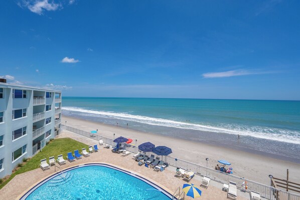 Un hotel con piscina, vista al mar y sillas de descanso.