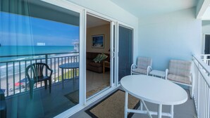 Ein Balkon mit Blick auf den Strand, einem Tisch und zwei Stühlen.