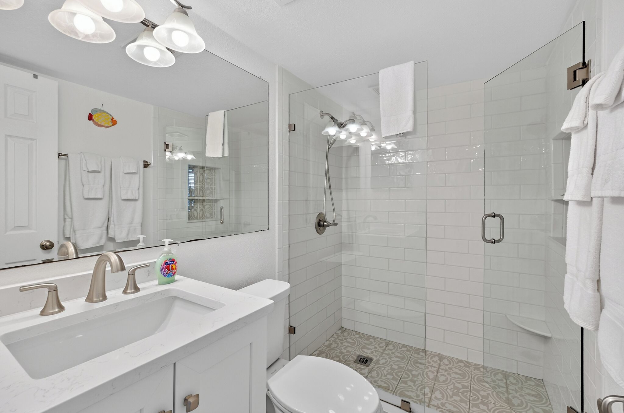 A bathroom with a sink, mirror, and shower.
