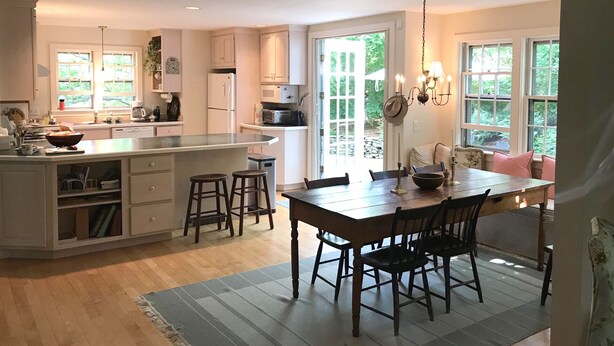 Une cuisine spacieuse avec un grand îlot central, une table à manger en bois et des chaises.