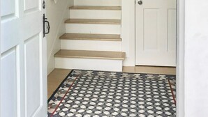 Un escalier aux murs blancs et un tapis à motifs menant à une porte.