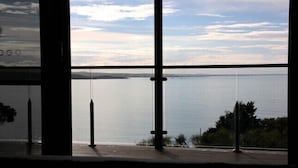 A view from a room with large windows overlooking a calm body of water and distant land. - SEA EAGLE COTTAGE Bay of Fires PEOPLES CHOICE TAS (Binalong Bay)