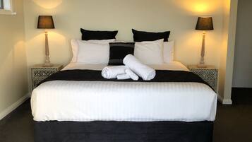 A neatly made bed with white and black bedding, two black pillows, and two bedside lamps on matching nightstands.