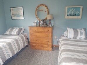 Ein Schlafzimmer mit zwei Betten, einem Schminktisch, einem Spiegel und Wandbildern.