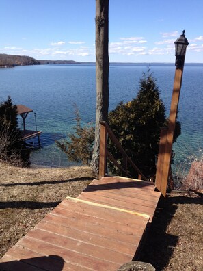 A wooden staircase leading to a gazebo by a lake with clear blue water and distant hills. - "Longview": FLX Lakefront Cottage w/Beachfront, Dock & Complimentary FLX Wine! (Ovid)