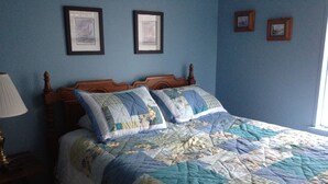 A bedroom with a wooden bed, a blue wall, and a window.