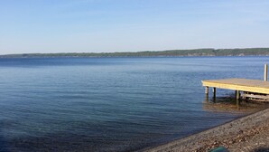 A wooden pier extending into calm waters with a clear view of a distant shoreline.