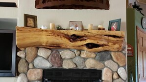 A stone fireplace with a log shelf above it, a television mounted on the wall, and a dog lying on the floor. - Beautiful Bison Ridge Cabin that has it all... (Show Low)