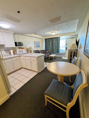 A compact living space with a kitchenette, a dining area with a round table and chairs, and a sofa.