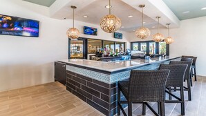 Eine Bar mit gefliestem Rückspritzgurt, Korbstühlen und Pendelleuchten.