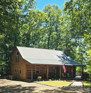 A log cabin with a metal roof, surrounded by trees. - Lake Cumberland custom log cabin home on 32 wooded acres (Nancy)