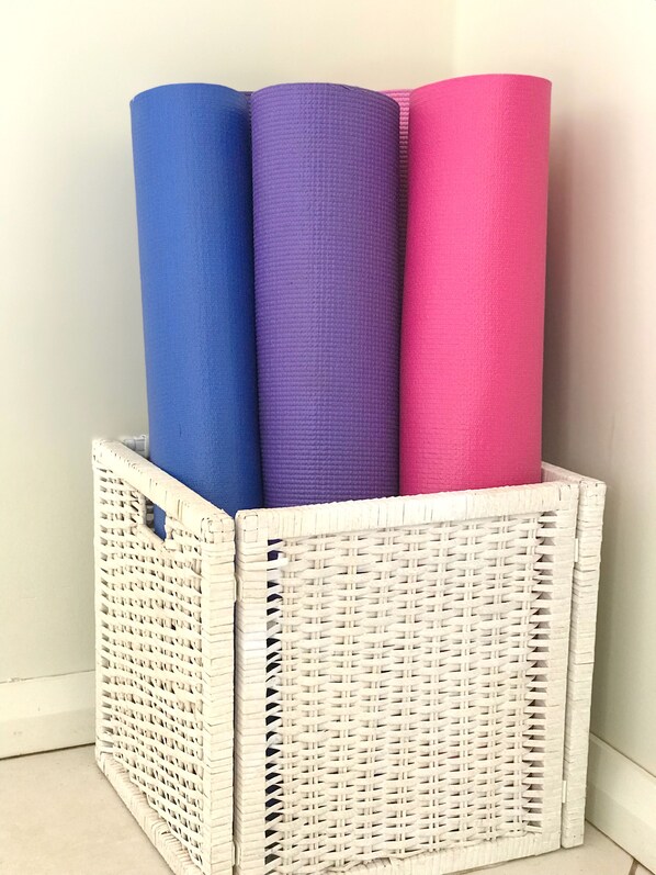 A wicker basket containing three rolled-up mats in blue, purple, and pink colors. - Waterfront modern property w/ boat, outside hot tub, SUPs, kayaks, fishing equip (Berowra Creek)