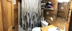 Een bad/douchecombinatie, handdoeken