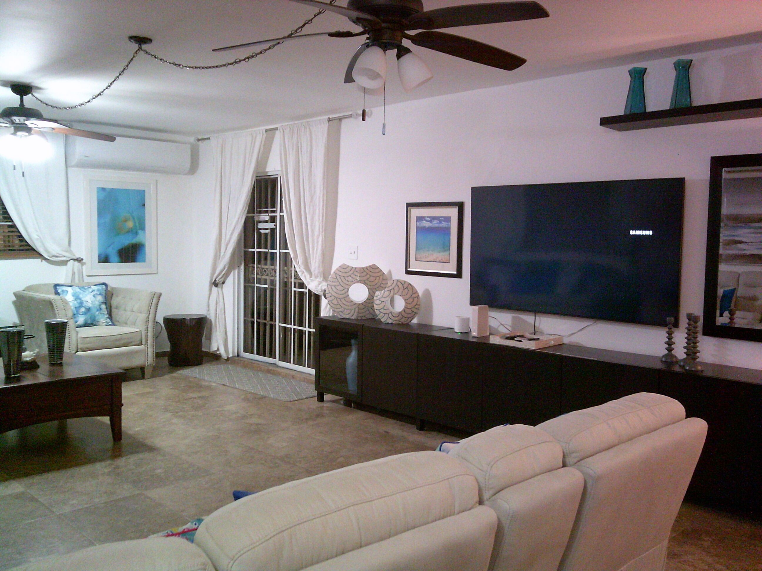 A living room with a sofa, a coffee table, a TV, and a ceiling fan.