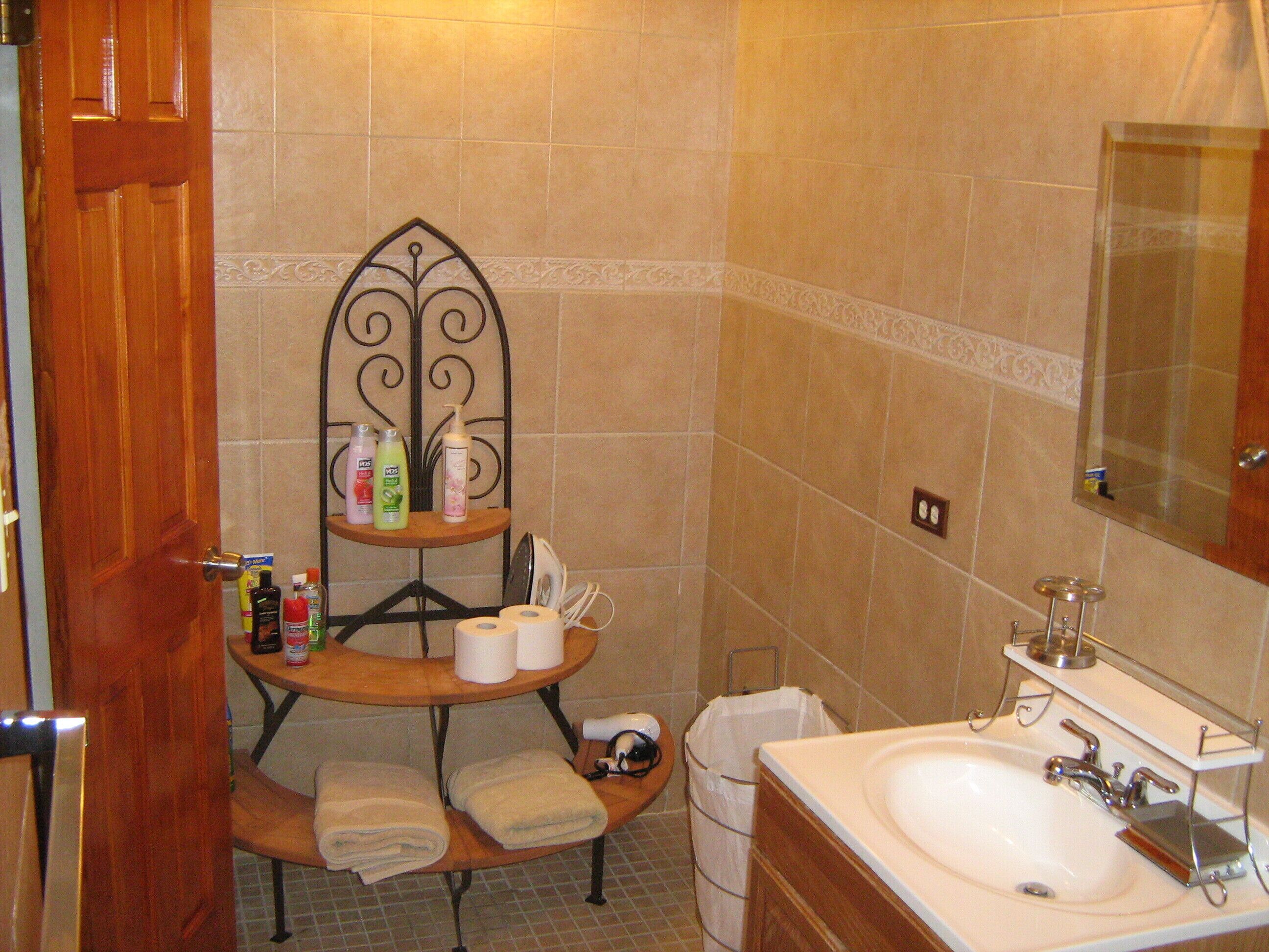 A bathroom with a sink, mirror, towel rack, and toiletries on a shelf.