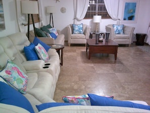 Una sala de estar con un sofá color beige, una mesa de centro y dos sillones.