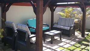 Een overdekt terras met rieten meubels en een blauwe bank.