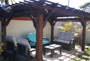 A covered outdoor seating area with wicker furniture and a blue sofa.