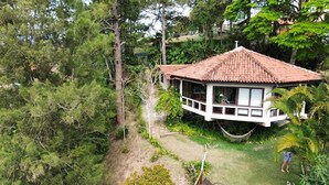 A bungalow with a tiled roof, surrounded by dense greenery and trees. - Cozy house, beautiful view, ideal for families and couples. OI FIBER INTERNET. (Petropolis)