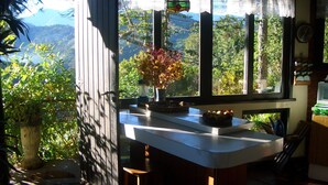 A kitchen with a large window, a hanging light fixture, and a view of a mountainous landscape. - Cozy house, beautiful view, ideal for families and couples. OI FIBER INTERNET. (Petropolis)