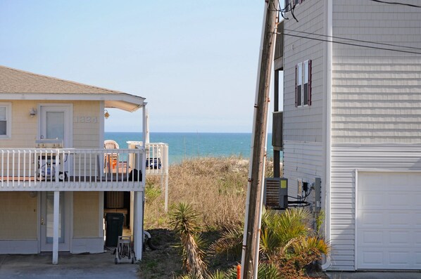 A coastal property with a balcony overlooking the sea, a garage, and a utility pole.