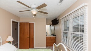 A bedroom with a bed, a ceiling fan, a dresser, a mirror, and a window with blinds. - Fun-N-The Sun - 2 BR Home; Dog Friendly with an Ocean View! (Surf City)