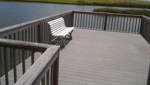 Une terrasse en bois avec un banc donnant sur une étendue d’eau.