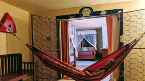A room with a bed, a hammock, and a view of another room.