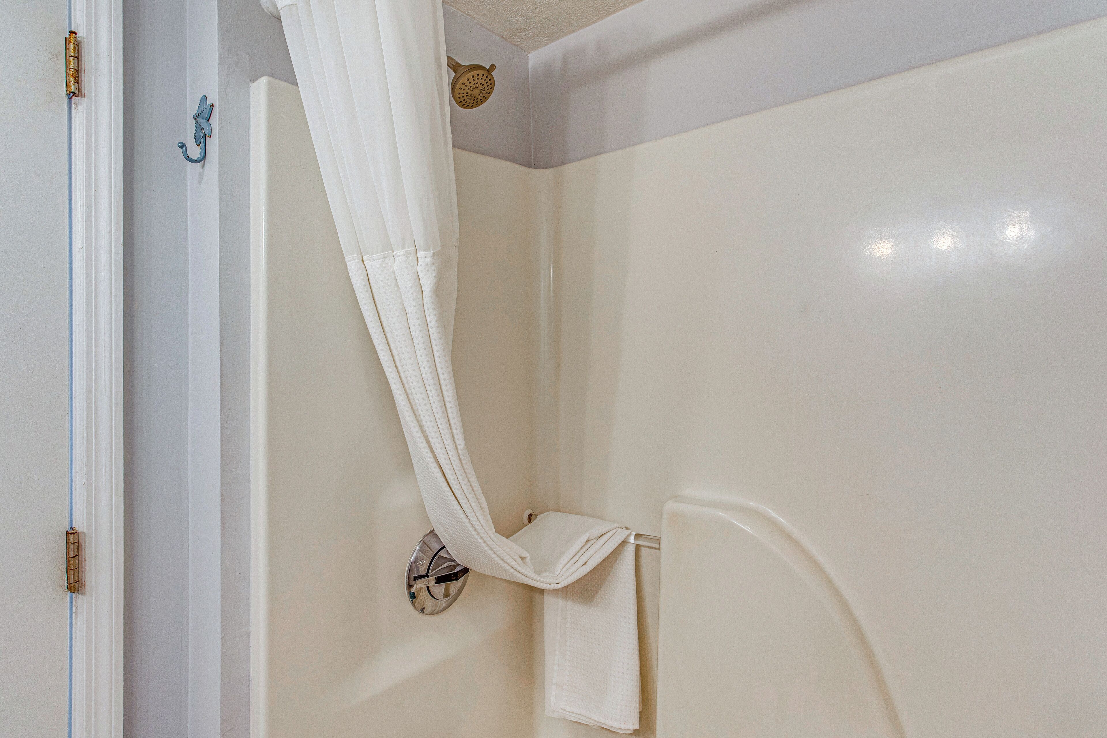 Un baño con ducha, un perchero y una puerta con cerradura.