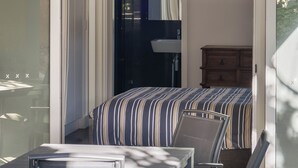 A room with a bed, a chair, a small table, and a cabinet. - “Oceanview & Seabreeze” - with Pool (Copacabana)
