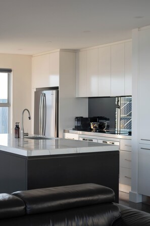 A modern kitchen with a central island, stainless steel appliances, and white cabinetry. - “Oceanview & Seabreeze” - with Pool (Copacabana)