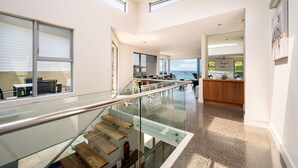 A modern interior with a glass staircase, a kitchen area, and a view of the sea. - “Oceanview & Seabreeze” - with Pool (Copacabana)