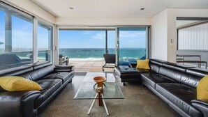 A modern living room with black leather sofas, a glass coffee table, and a view of the ocean through large sliding glass doors. - “Oceanview & Seabreeze” - with Pool (Copacabana)